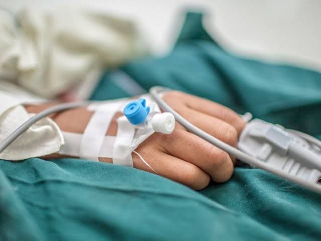 Child's hand with an IV line and pulse oximeter resting on a surgical drape